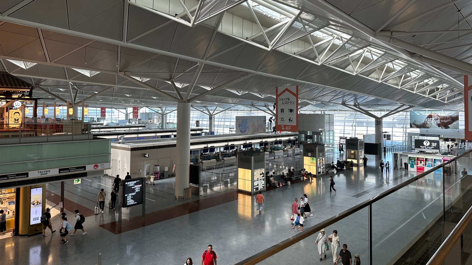 Wide photograph of Chubu Centrair International Airport check-in hall in Nagoya, with travellers and terminal wayfinding.