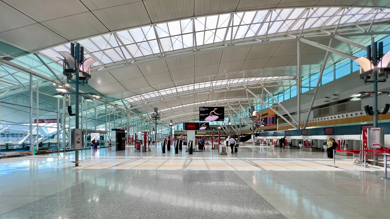 Archive photograph of Sydney Airport Terminal3 check-in hall, with counters, travellers and a glazed structural roof, December2022.